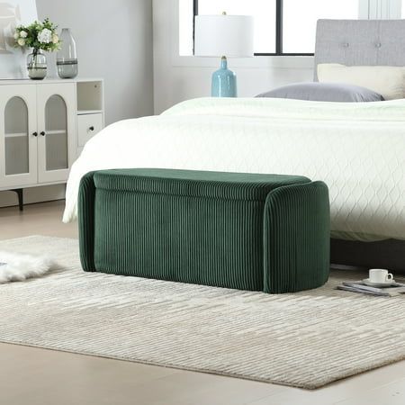 a bed sitting on top of a white rug next to a green footstool