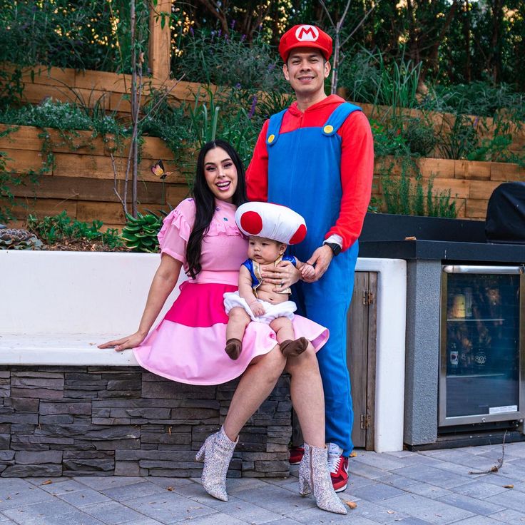 a man and woman in mario costume posing for a photo with a child on their lap