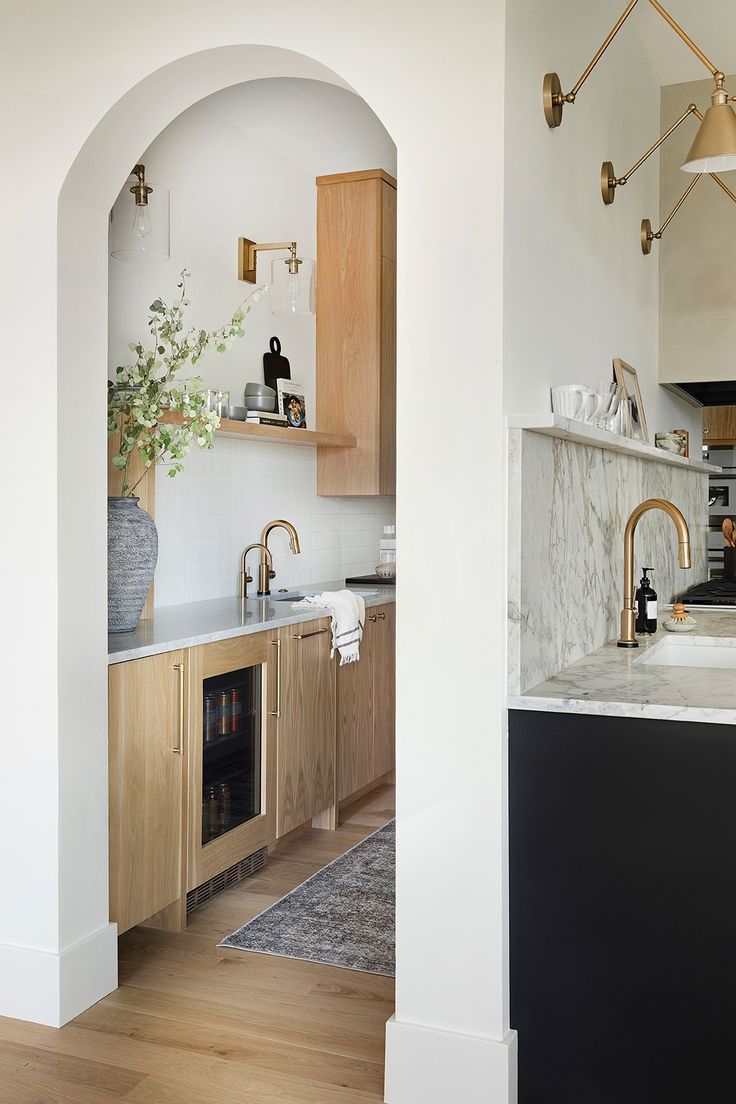 a kitchen with wooden cabinets and marble counter tops, along with an arched doorway leading to the dining room