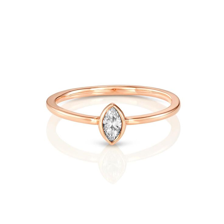 a rose gold ring with a pear shaped diamond in the center, on a white background