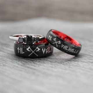 two black and red rings with crosses on them sitting on top of a wooden table