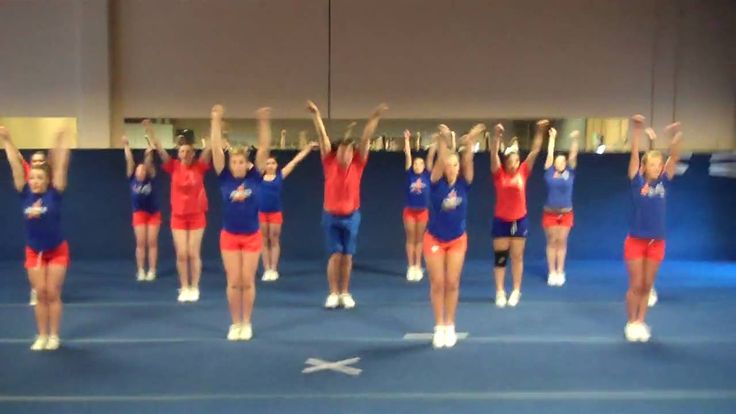 a group of cheerleaders standing on top of a blue floor with their arms in the air