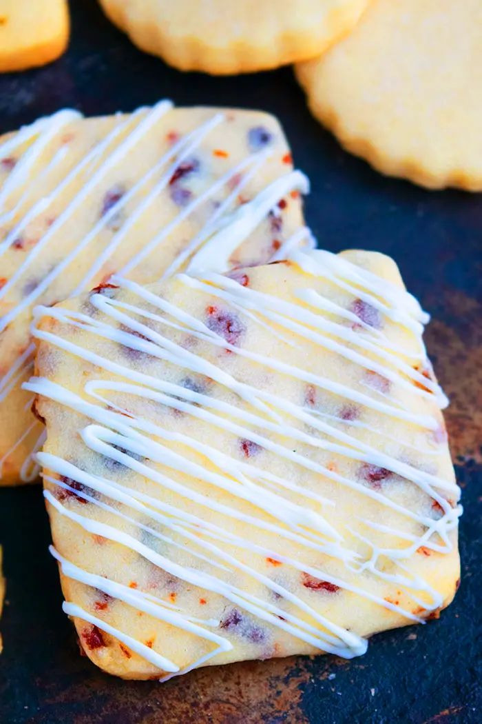 cookies with white icing and cranberry toppings on a baking sheet, ready to be eaten