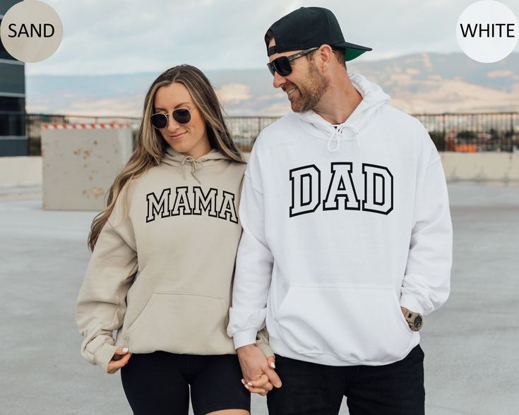 a man and woman holding hands while wearing matching hoodies