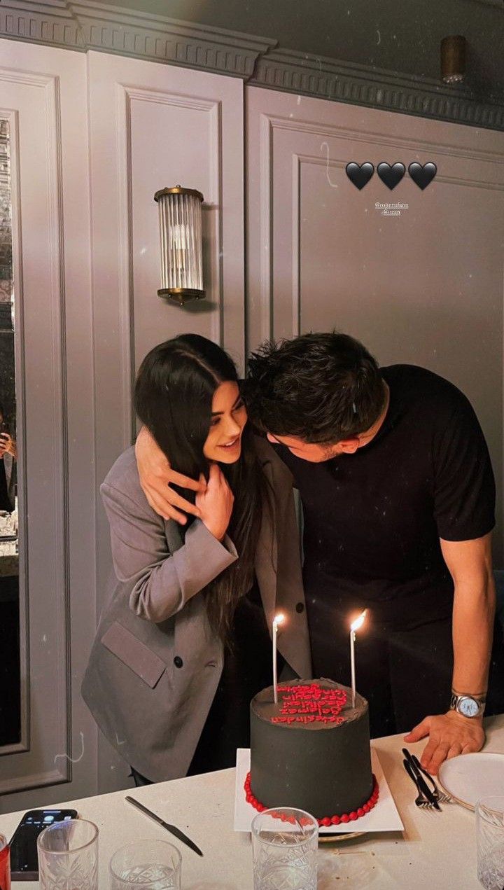 a man and woman standing next to each other in front of a cake with candles