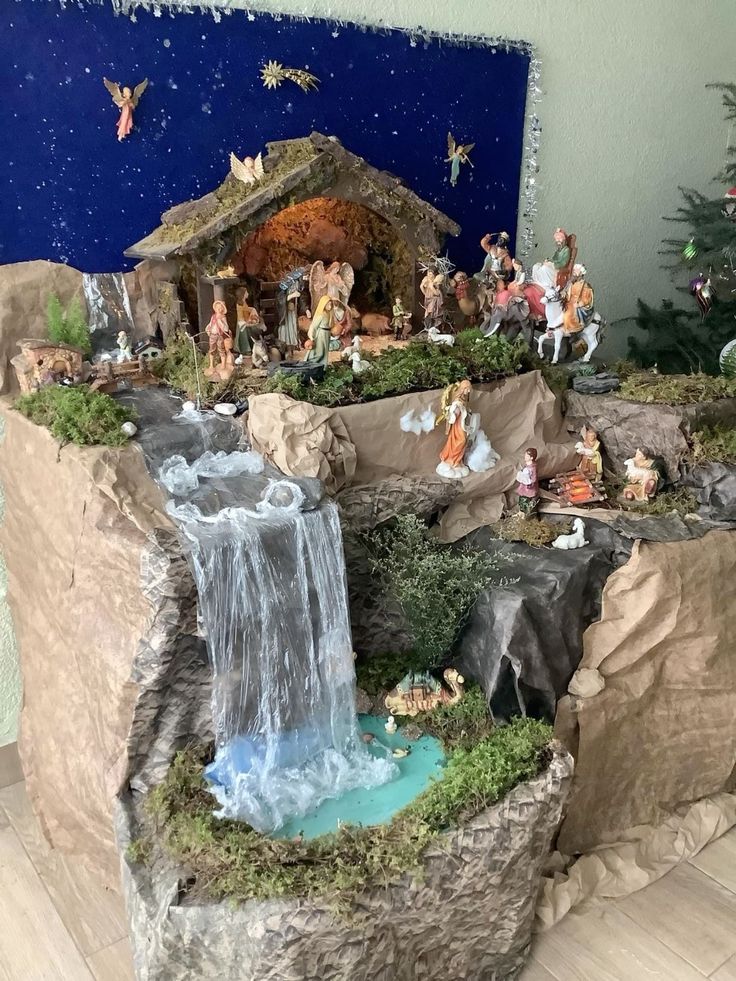 a nativity scene is displayed on the wall next to a christmas tree and small waterfall