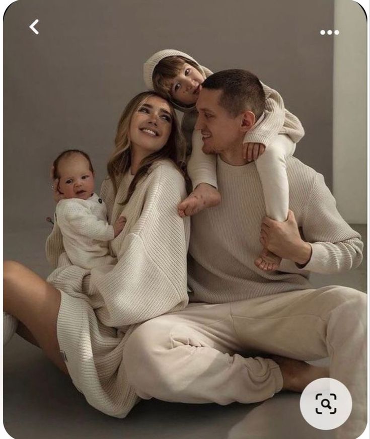 a man and woman are sitting on the floor with their two children in front of them