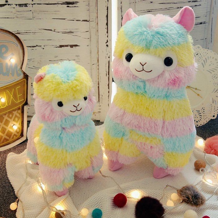 two stuffed llamas sitting on top of a table with lights and decorations around them