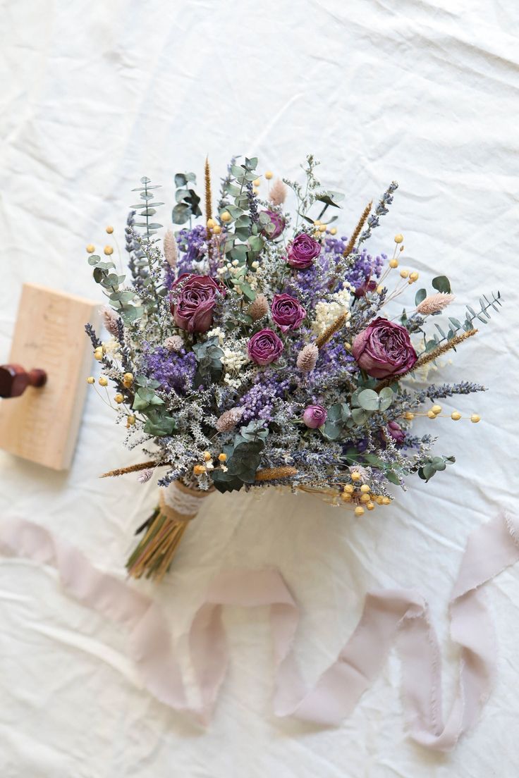 a bouquet of flowers sitting on top of a white table cloth next to a piece of paper