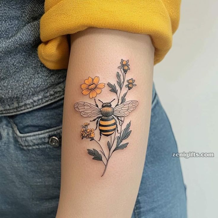 a woman's arm with a bee and flowers tattoo on the back of her arm