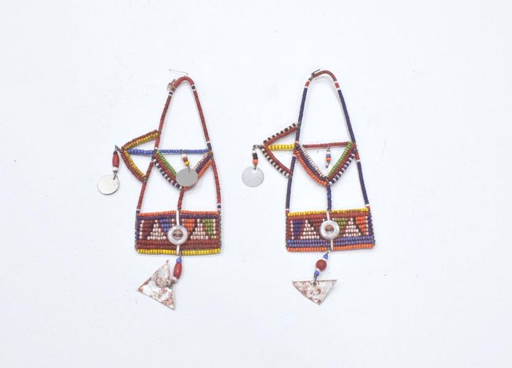 These African old tribal beaded earrings from the Masai Tribe of Kenya and would be a stunning addition to any jewelry collection. The intricate design and vibrant colors make them a true statement piece. The earrings are made from wire and beads and feature a unique aluminum metal. The earrings are collectors items and are perfect for both men and women. The main stone is glass and the ear area is the lobe. The beaded style and multicolor design are a beautiful representation of African ethnic and regional style of the Masai of Kenya. These earrings are a must-have for anyone who loves tribal jewelry. Museum Quality 6 Inches Long 3 Inches Wide Middle Top 2 1/4 Inches Wide Bottom Dangle 1.5 Inches Long AT BACARA WE STAND BEHIND ALL OF OUR MERCHANDISE. FULL MONEY BACK GUARANTEE WILL BE PROV Multicolor Metal Earrings For The Beach, Multicolor Metal Earrings For Beach, Traditional Beaded Earrings For Festival, Unique Multicolor Earrings With Tiny Beads, Bohemian Earrings With Silver Beads For Festivals, Multicolor Metal Beaded Earrings, Artisan Metal Beaded Earrings With Dangling Beads, Multicolor Metal Festival Earrings, Traditional Metal Beaded Earrings For Festivals