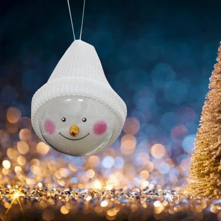 a snowman ornament hanging from a string next to a christmas tree with lights in the background