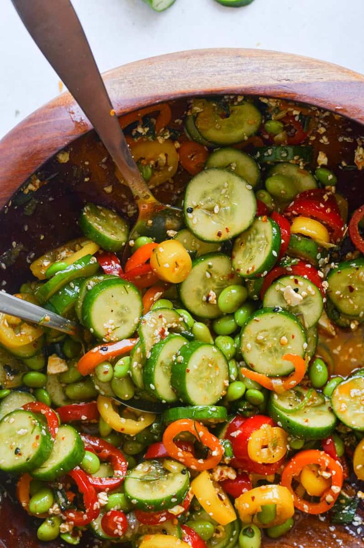 a wooden bowl filled with cucumbers and peppers