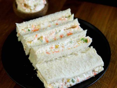 there is a sandwich cut in half on a black plate with other food items around it