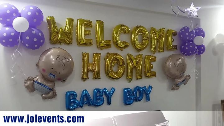 the welcome home sign is decorated with balloons and baby's breathes in gold, silver and purple colors