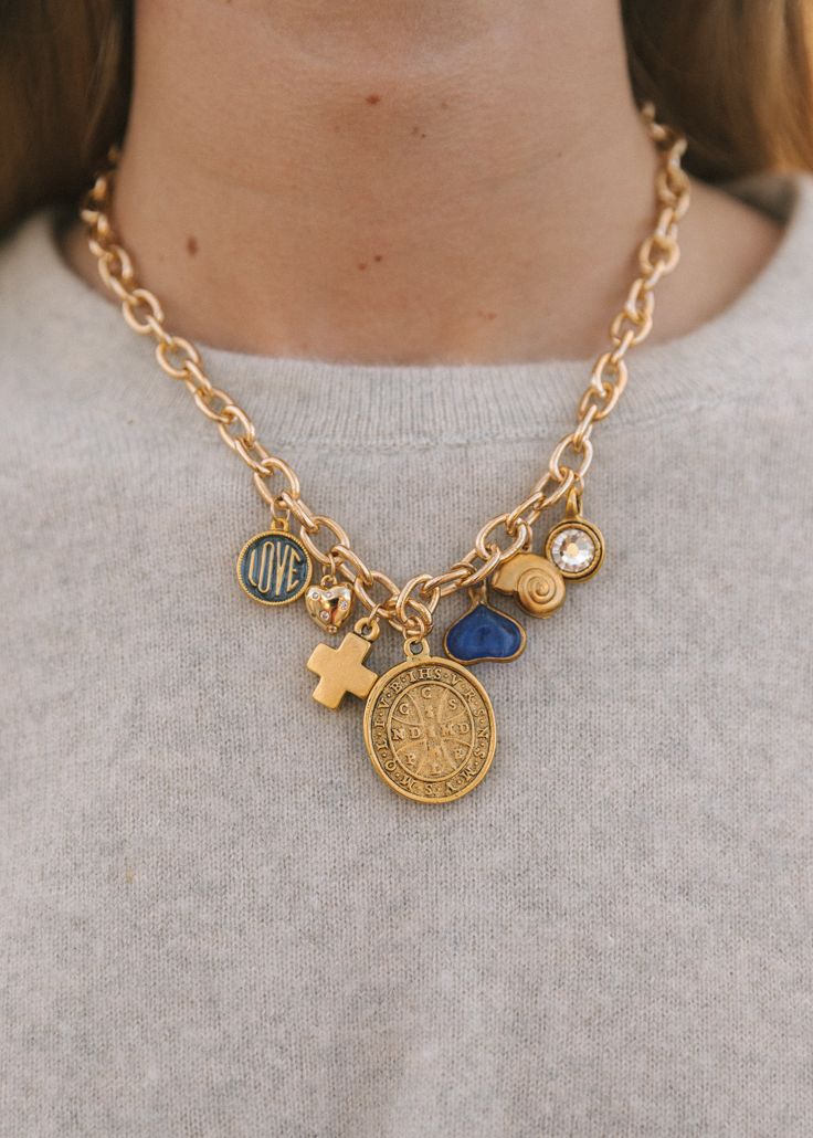 Elevate your style with our 16" gold-filled chain vintage-inspired charm necklace. This exquisite piece features seven unique charms: St. Benedict coin, gold cross, mini heart with rhinestones, love pendant, bezeled rhinestone charm, vintage spiral shell, and a playful blue fun heart. A perfect blend of elegance and ch Coin Charm Necklace, Funky Necklaces Jewelry, Gold Pendant Charm Necklace, Charm Necklace Outfit, Diy Charm Necklace Ideas, Vintage Charm Necklace, Chunky Charm Necklace, Charm Necklace Aesthetic, Charm Necklace Ideas