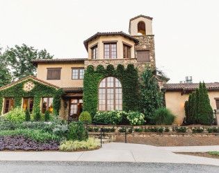 a large house with lots of plants growing on it's sides and an entry way leading to the front door