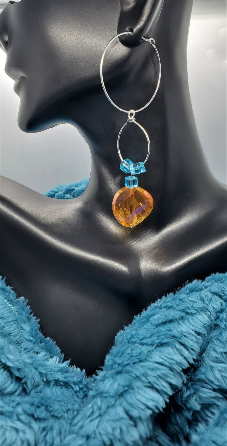 Create an eye-catching summer look with these gorgeous Amber Sparkle Earrings! Constructed from amber and aqua blue stones set in a silver design, these lightweight earrings exude elegance and bring an upbeat feel to any ensemble. Perfect for adding a touch of girly charm to any outfit, Amber Sparkle Earrings are sure to make a statement. Amber Sparkle Earrings Details: silver hoop style orange and gold color 3"drop round shaped 100% glass sparkling design 18 mm faceted amber bead girly girl sty Silver Topaz Dangle Earrings, Silver Teardrop Topaz Earrings, Silver Topaz Teardrop Earrings, Topaz Earrings For Pierced Ears, Blue Fusion Drop Earrings, Blue Fusion Earrings For Pierced Ears, Blue Fusion Style Drop Earrings, Blue Fusion Dangle Earrings, Fusion Style Blue Gemstone Earrings