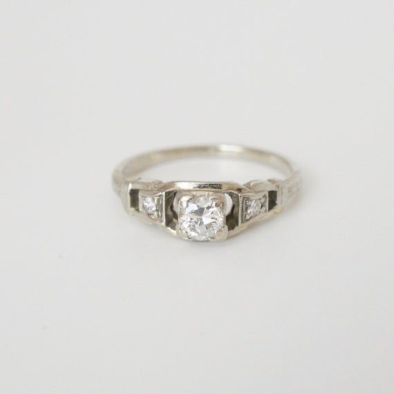 a diamond ring with three stones on the side, set in 18k white gold