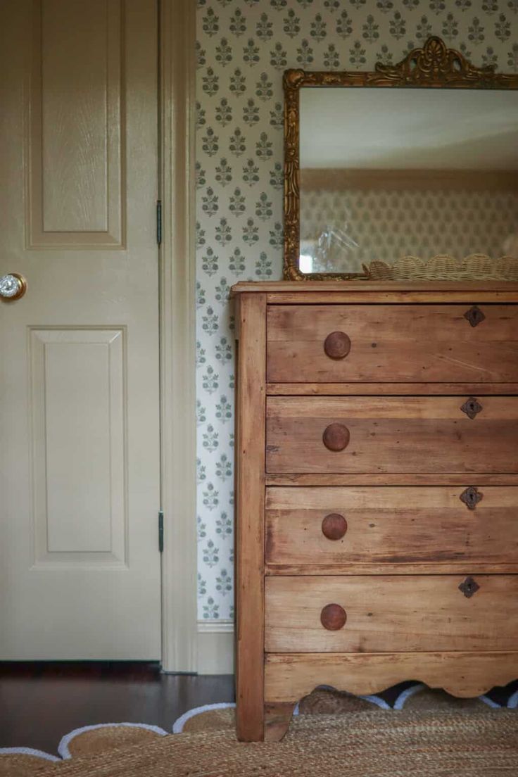 a wooden dresser sitting in front of a door with a mirror on top of it