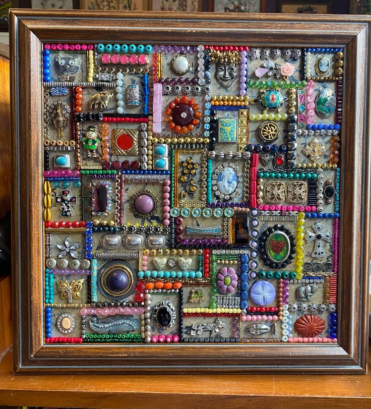 a wooden frame filled with lots of different colored beads and buttons on top of a table