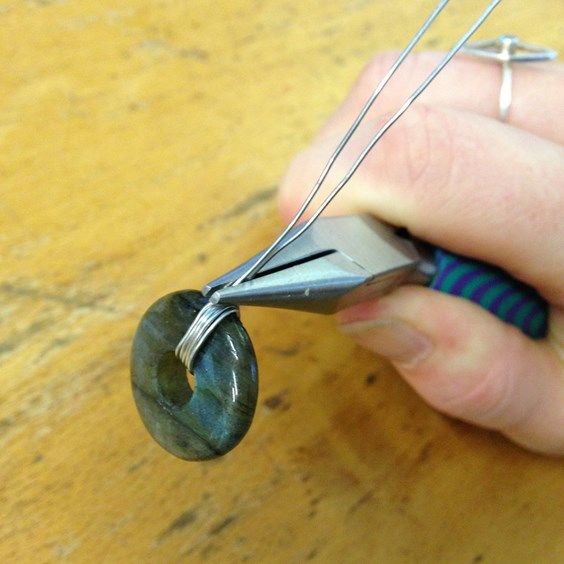 a person is holding a pair of scissors and threading it to the end of a piece of wire