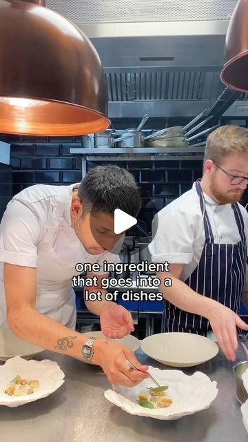 two men are in the kitchen preparing food on plates and one man is holding a knife