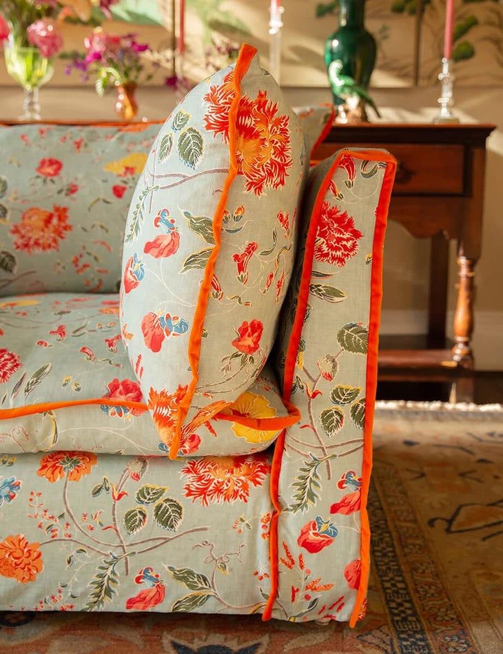 a floral couch with orange trim on it