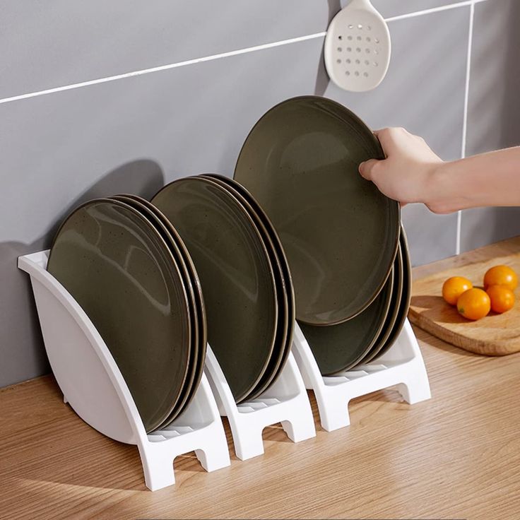 a person is placing plates on a rack in front of a counter with oranges