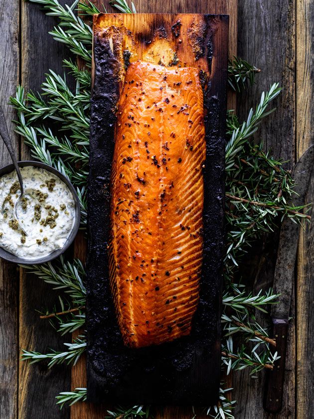 a cooked salmon on a cutting board with herbs