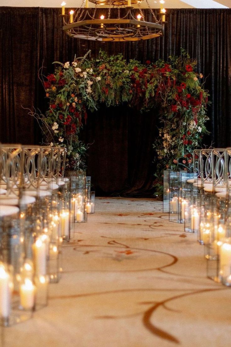 the aisle is lined with candles and decorated with greenery, red roses and white flowers