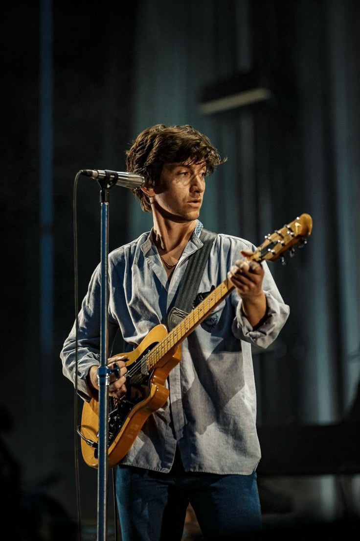 a man holding a guitar while standing in front of a microphone