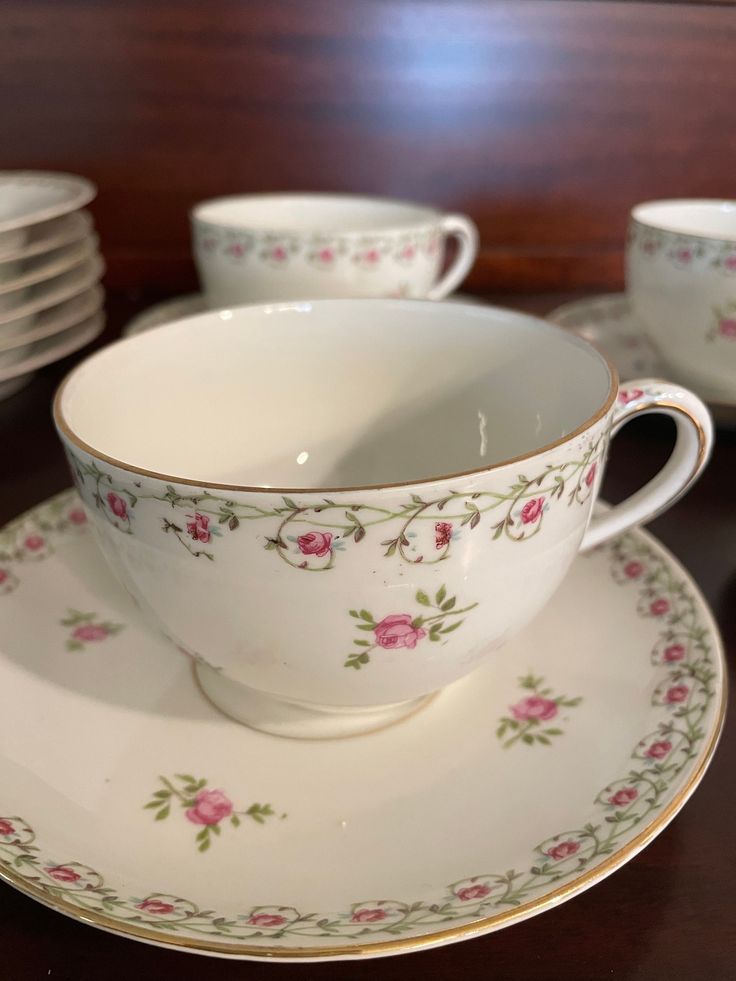 a tea cup and saucer sitting on top of a table next to stacks of plates