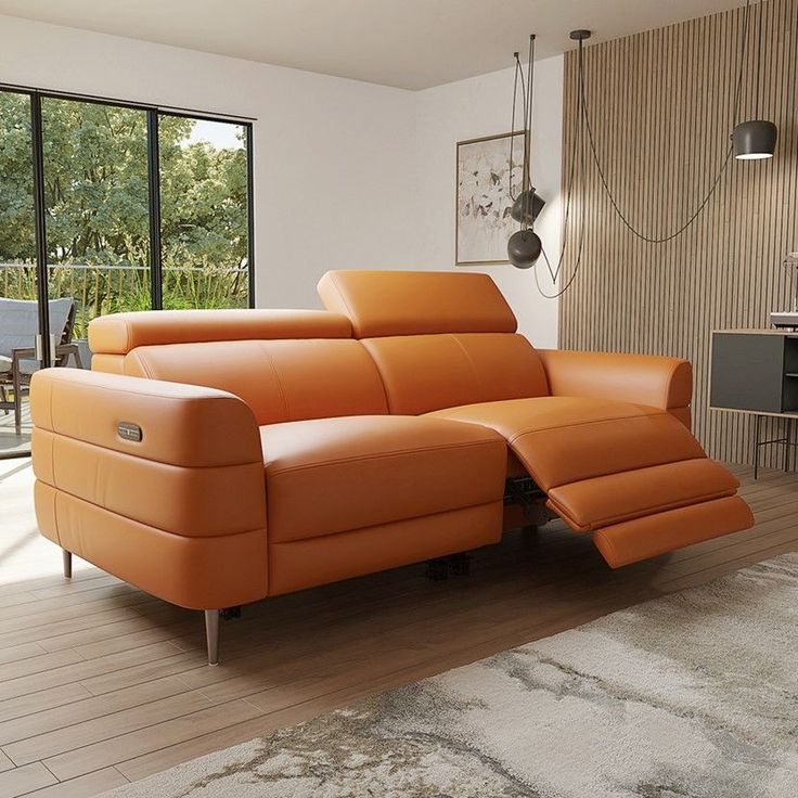 an orange leather couch sitting on top of a wooden floor next to a glass wall