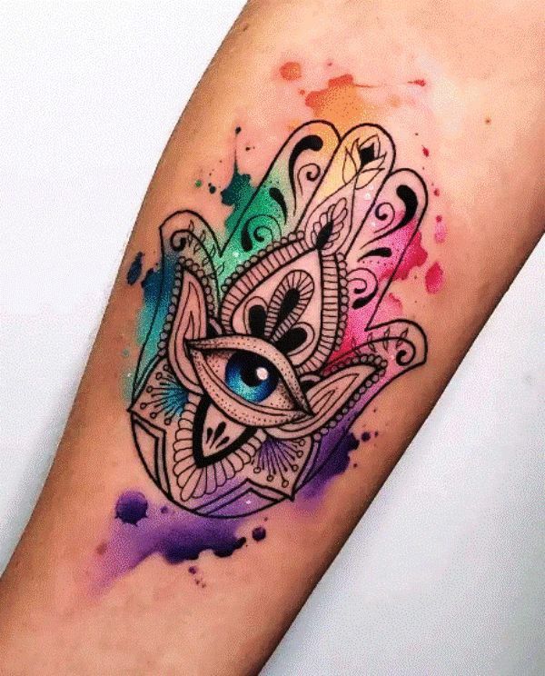 a colorful hamsa tattoo with an eye on it's arm and watercolor splashs