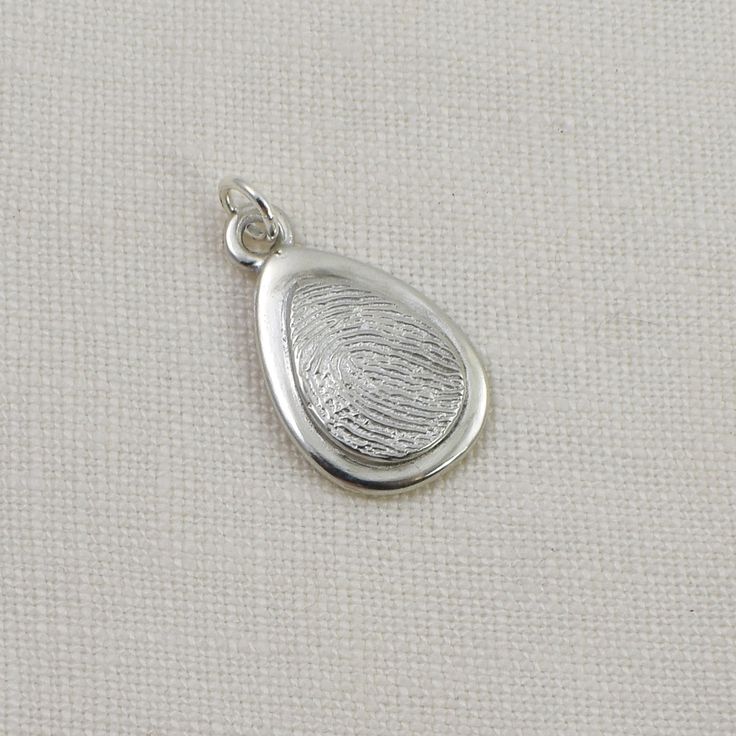 Keep your loved one with you always, with this lovely fingerprint teardrop pendant that combines elegance and sentimentality. Handcrafted in solid sterling silver, this pendant features a sleek silver oval layered with a smaller oval fingerprint, creating a unique and personalized accessory. The raised fingerprint accentuates its importance and draws attention to the beautiful details of the print. The smooth edges and shiny finish of the pendant give it a sophisticated touch, making it suitable Sterling Silver Teardrop Charms Jewelry, Classic Drop Earrings With Polished Finish For Gift, Teardrop White Gold Sterling Silver Jewelry, White Gold Sterling Silver Teardrop Jewelry, Silver Teardrop Charms Jewelry, Minimalist Teardrop Pendant Drop Gift, Minimalist Teardrop Pendant As A Gift, Minimalist Teardrop Pendant For Gift, Minimalist Silver Teardrop Pendant