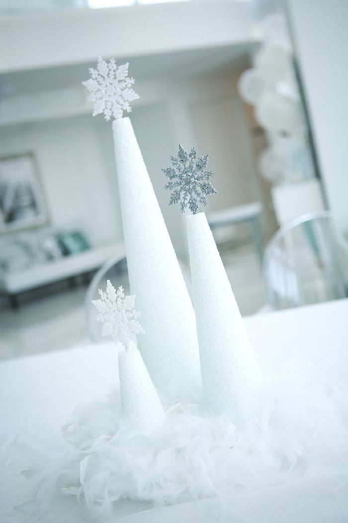 three white cones with snowflakes on them sitting on a table in front of a mirror