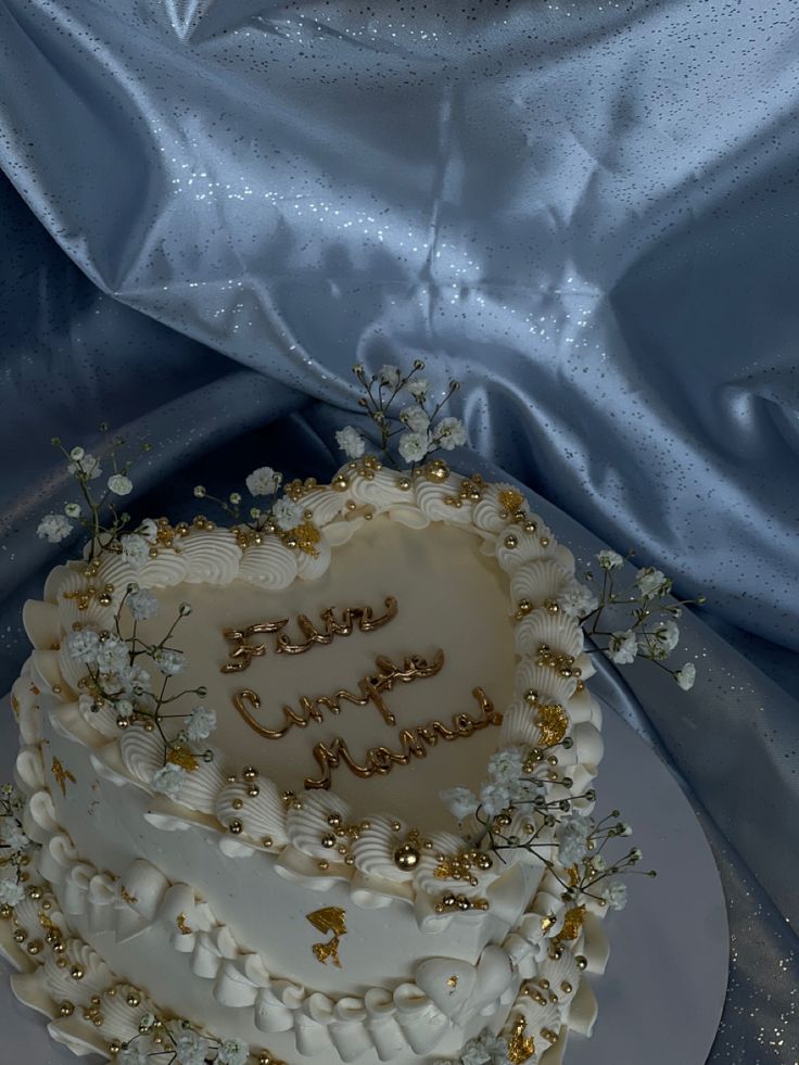 a heart shaped cake sitting on top of a table next to a blue sheet covered cloth