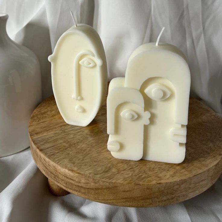 two white candles sitting on top of a wooden stand