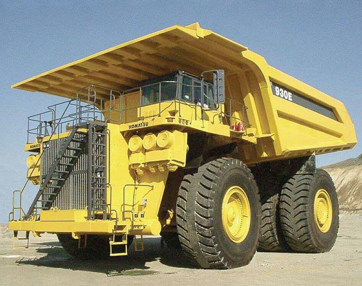 a large yellow dump truck parked on top of a dirt field