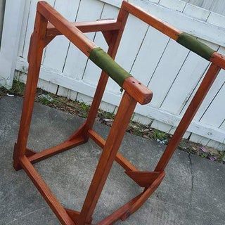 a wooden chair sitting on top of a cement floor next to a white picket fence