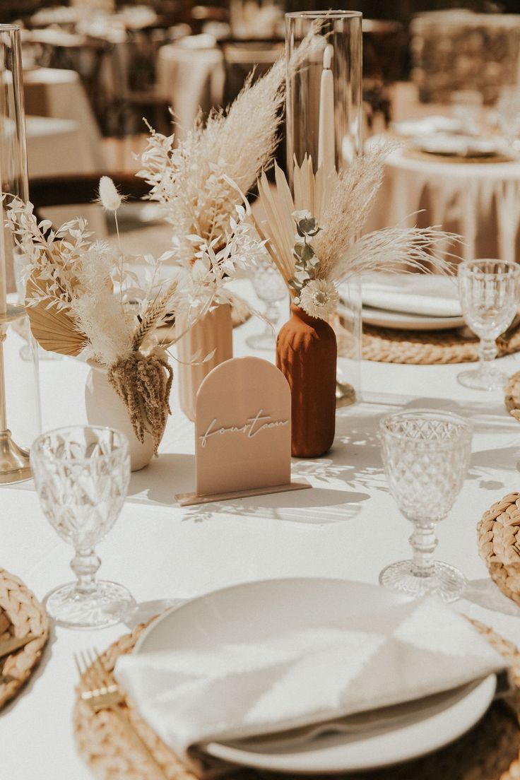 the table is set with white plates and place settings for guests to sit down at