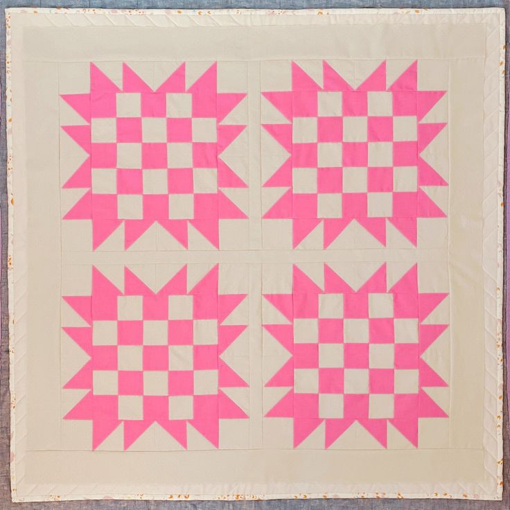 two pink and white quilts are on the ground with one block in the middle