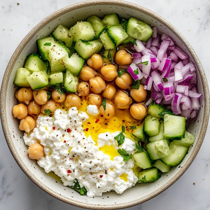 a bowl filled with cucumber, chickpeas, onions and yogurt