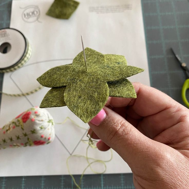 someone is holding up some green felt leaves