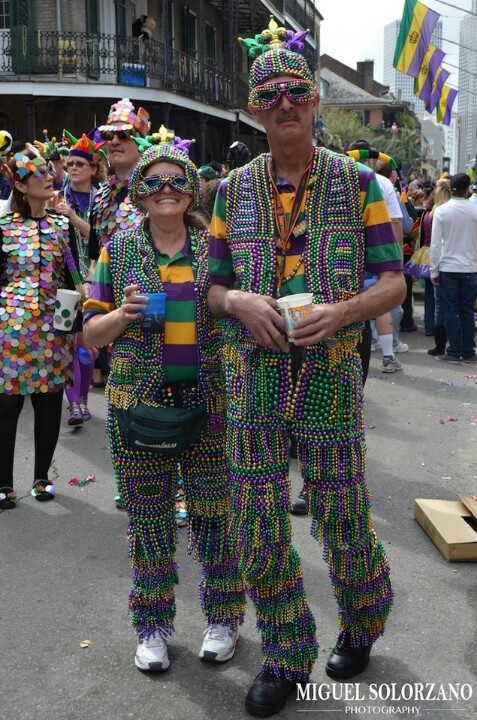 two people dressed in colorful clothing standing next to each other on the street with confetti all around them