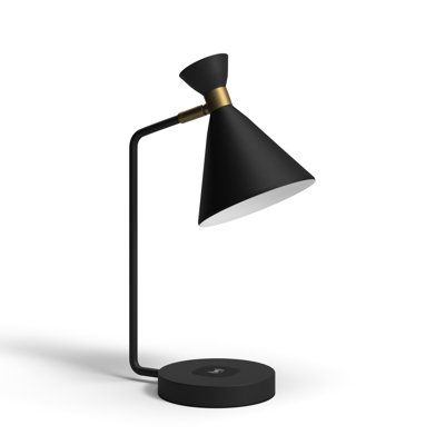 a black and gold desk lamp with a white light on the top, next to a round base