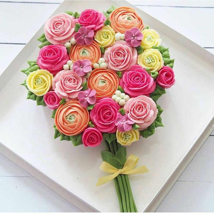 a bouquet of colorful flowers sitting on top of a white square plate with yellow ribbon