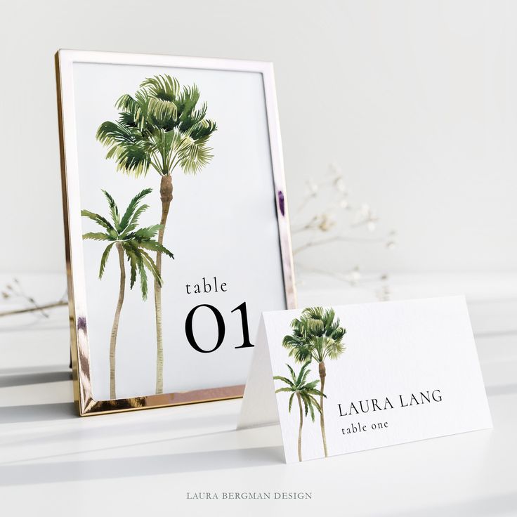 a table number and place card holder with palm trees on the front in gold frame