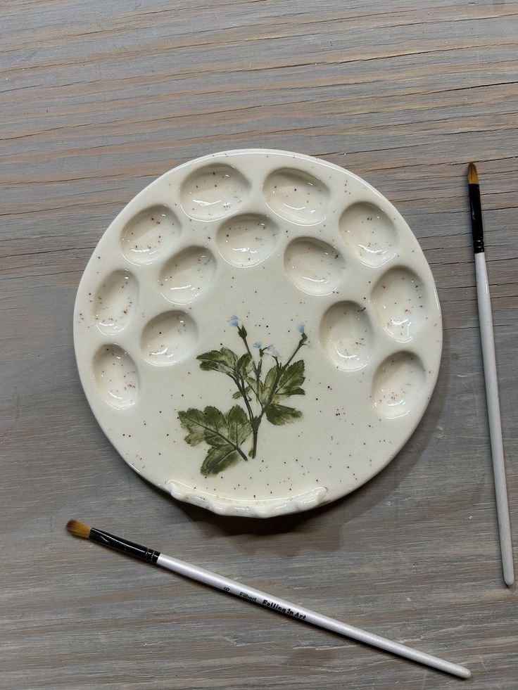 a white plate with some paint on it next to a brush